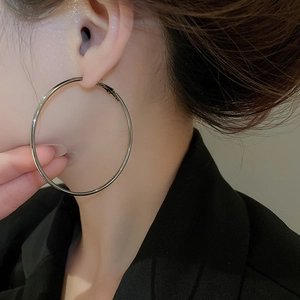 Close-up of stylish large silver metallic hoop earring worn by a female model