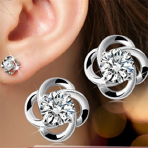 Macro shot of silver clover earrings with sparkling zircon on model ear