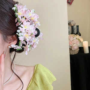 Close-up of pink fabric cherry blossom hair clip worn on model hair with soft floral detail