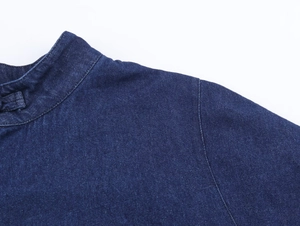 Detailed view of the dark blue denim cape top stitching and textured fabric quality