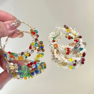 Détail macro de perles de verre colorées enroulées sur des créoles dorées avec tiges en argent