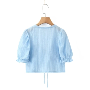 Détail du haut à manches bouffantes bleu clair avec texture et bordure en dentelle