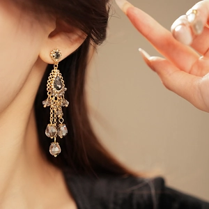 Close-up of vintage gold tassel earrings with dark crystal drops and intricate bohemian details