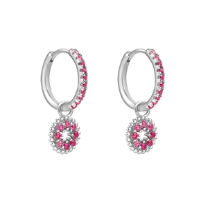 Détail de boucles d'oreilles créoles argentées avec pierres roses et pendentif cœur