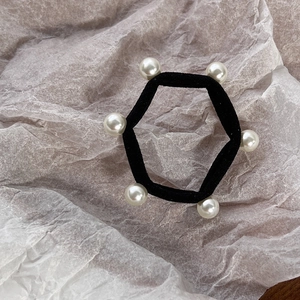 Detail view of elastic hair tie featuring six white faux pearls in a hexagonal layout