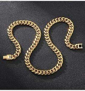 Detail of a golden stainless steel Cuban link chain with a square clasp on black texture