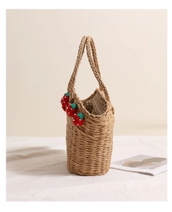 Detailed close-up of handmade red crochet strawberries and white beads on a straw tote