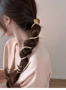 Detail shot of a beige heart-shaped phone cord hair tie styling a braided ponytail