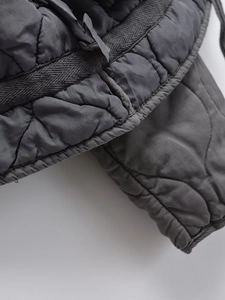 Detailed close-up of dark grey diamond quilting and thick hem on high-quality winter jacket