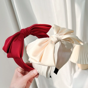 Close-up of red and beige satin bow headbands with a luxury silk texture for women