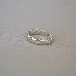 Detailaufnahme eines silbernen gedrehten offenen Rings auf grauem Hintergrund