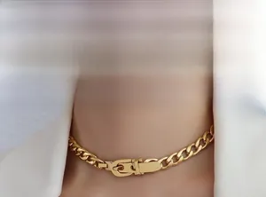 Macro view of golden chunky chain necklace featuring a modern belt buckle clasp design