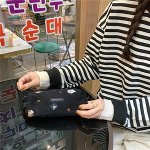 Close-up of black canvas pencil case with cute cat embroidery and zipper ring