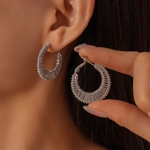 Silver textured C-shape hoop earrings with woven metal finish worn by model