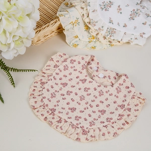 Detailed texture of floral cotton baby bibs with delicate ruffle trim and snap closure