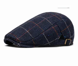 Detail of navy blue plaid flat cap featuring herringbone tweed and adjustable bronze buckle