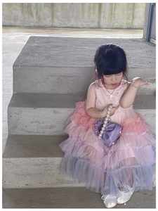 Detail of a purple pleated bucket bag with a pearl handle held by a child model