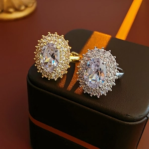 Detail of oval-cut zircon rings in gold and silver finish on luxury leather jewelry box
