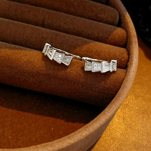 Macro shot of silver fan-shaped geometric ear cuffs set with white zircon in a jewelry box
