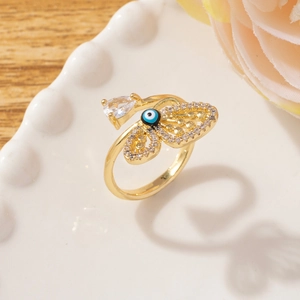 Detail of gold evil eye ring featuring micro-pave butterfly wing and pear-cut zircon