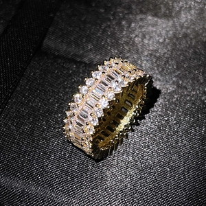 Macro view of wide gold ring with rows of rectangular and round cut clear zircons