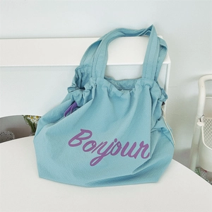 Detail of blue waffle texture nylon tote bag with purple Bonjour print and drawstring