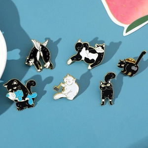 Detail view of six cartoon black and white enamel cat pins with gold metal edges