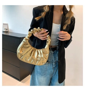 Model styling a metallic gold cloud-shaped handbag with elegant ruched handle details