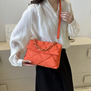 Detail of orange quilted nylon crossbody bag with bold plastic chain handle and strap