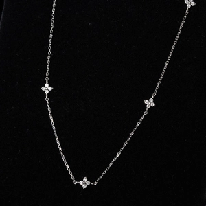 Detail of four silver clover pendants with micro-set zircons on black velvet background
