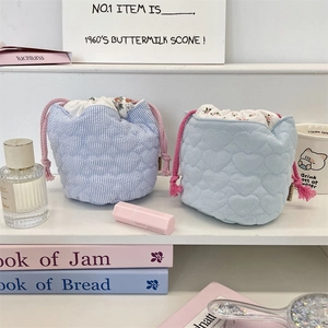 Detail view of quilted drawstring storage bags with heart patterns and floral lining