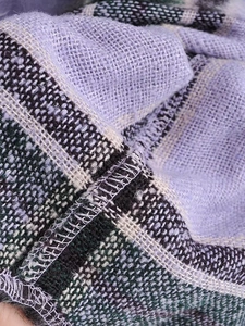 Detailed macro view of purple plaid wool coat fabric texture and premium knitted edges