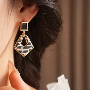 Detail of luxury geometric resin earring with silver needle and gold frame on model