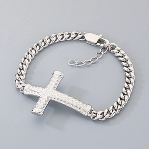 Détail du bracelet gourmette argentée avec pendentif croix texturée et fermoir homard