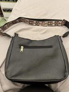 Detail of black pebbled leather crossbody bag with ethnic jacquard wide shoulder strap