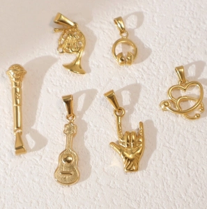 Detailed view of six gold stainless steel musical and medical charms like guitar and mic