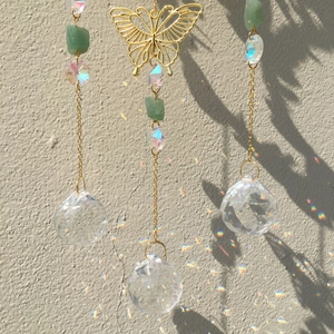 Macro shot of three crystal prisms and green gemstone shards reflecting sunlight