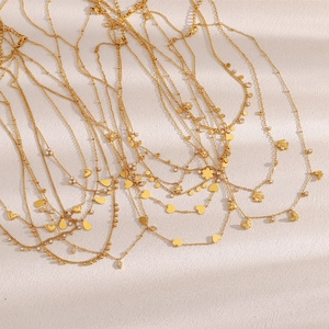 Detail of 18K gold plated stainless steel layered necklaces with heart and flower pendants