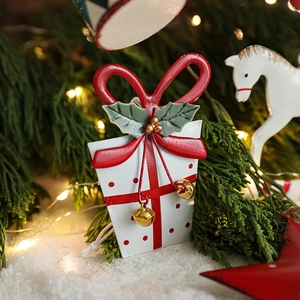 Hand-painted metal Christmas gift box ornament with bells hanging on a festive tree
