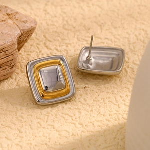 Vista macro di orecchini a perno geometrici quadrati con finitura bicolore oro e argento