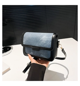 Detail of denim and PU leather patchwork bag with golden magnetic clasp and adjustable strap