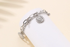 Detail of silver double-layer sun pendant bracelet with paperclip chain and metal beads