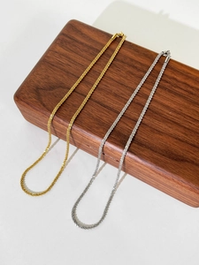 Close-up of shimmering gold and silver titanium steel snowflake chains on wooden stand