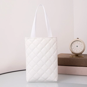 Close-up of white quilted PU leather tote bag on glass table with elegant props
