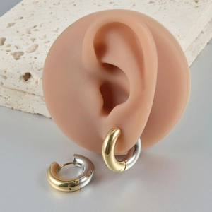 Detailed view of two-tone silver and gold hinged hoop earrings on silicone ear model