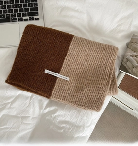 Detail of color-block knit scarf showing caramel and beige ribbed texture and woven label