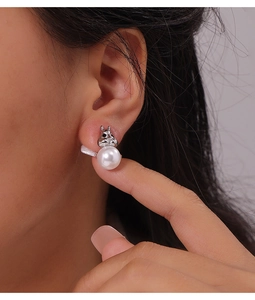 Close-up of rabbit-shaped titanium earrings with elegant white pearl on model ear