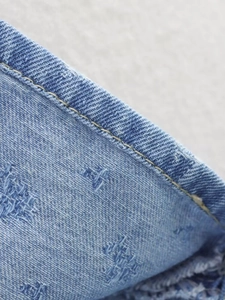 Dettaglio ravvicinato del denim blu lavato con effetto consumato e cuciture doppie rinforzate
