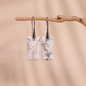 Minimalist white marble rectangle drop earrings with silver hooks on a natural branch