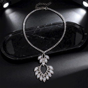 Close-up of sparkling silver hollow leaf pendant with zircons on black marble tray